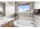Bright bathroom featuring a soaking tub with tile surround and large window at 19064 E Oak Creek Way, Parker, CO 80134