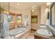 Bright bathroom with double sinks, soaking tub and exterior views from multiple windows at 28532 Hummingbird Hill Rd, Conifer, CO 80433