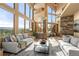 Bright living room features a neutral palette, walls of windows with stunning outdoor views, and stone accents at 28532 Hummingbird Hill Rd, Conifer, CO 80433