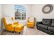 Cozy living room featuring bright armchairs, a dark leather sofa, and large window at 9765 Merimbula St, Highlands Ranch, CO 80130