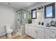 Modern bathroom featuring glass-enclosed shower, white cabinets, and marble countertops at 7930 Alkire St, Arvada, CO 80005