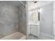 Well-lit bathroom boasts stone tiled walls, a tub, and a vanity with modern lighting fixtures at 7930 Alkire St, Arvada, CO 80005