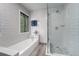 Bright bathroom with a tub, separate shower, and modern gray and white tile at 7930 Alkire St, Arvada, CO 80005