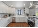 Bright renovated kitchen with white cabinets, stone backsplash, stainless steel appliances, and hardwood floors at 7930 Alkire St, Arvada, CO 80005