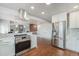 Contemporary kitchen featuring stainless steel appliances, modern vent hood, and adjoining living space at 7930 Alkire St, Arvada, CO 80005