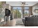 Bright living room features a stone fireplace, large windows, hardwood floors, and balcony access with views at 8922 S Tuscany Ln, Highlands Ranch, CO 80130