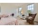 Comfortable bedroom showcasing a rocking chair and changing table, illuminated by natural light from large windows at 15649 E 7Th Cir, Aurora, CO 80011