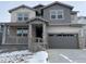 Two-story home featuring varied gray siding, stone accents, covered front porch, and two-car garage, offering classic curb appeal at 585 Twilight St, Erie, CO 80516