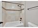 Modern bathroom tub and shower with beige tile, dark fixtures, and a mosaic accent at 12762 Fisher St, Englewood, CO 80112