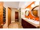 Bathroom with double sinks, wood cabinetry, and orange wall, plus a shower and walk-in closet at 10601 E Crestline Ave, Englewood, CO 80111