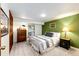 Cozy bedroom with an inviting bed, dresser with mirror, and calming green accent wall at 10601 E Crestline Ave, Englewood, CO 80111