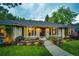 Lovely brick home featuring a well-manicured lawn, colorful flowerbeds, and a charming walkway leading to the entrance at 10601 E Crestline Ave, Englewood, CO 80111