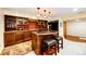 Basement bar area, complete with wood cabinetry, island seating, and ample storage at 10601 E Crestline Ave, Englewood, CO 80111