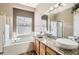 Bright bathroom with double sinks, granite countertops, a large window over a soaking tub, and shower at 3080 Madison Ln, Broomfield, CO 80023