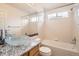 Bright bathroom featuring a glass bowl sink, granite countertop, tiled walls, and tub with shower at 3080 Madison Ln, Broomfield, CO 80023