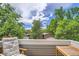 Balcony with wooden chair and table set against a backdrop of leafy green trees at 1430 18Th St # 16, Boulder, CO 80302