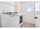 Bright laundry room featuring a modern washer and dryer, sleek shelving, and a well-lit window at 7756 S Eaton Park Ct, Aurora, CO 80016