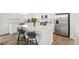 The kitchen island features seating and a quartz countertop adjacent to the stainless steel refrigerator at 1884 Myron Ct, Erie, CO 80516