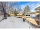 Spacious backyard with snow-covered lawn, mature trees, fence and carport at 1173 Xenon St, Golden, CO 80401