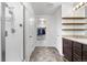 Bright bathroom featuring a walk-in shower, wooden shelves, and dual-sink vanity at 42853 Ivydel St, Elizabeth, CO 80107