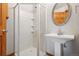 Bathroom featuring a pedestal sink, chrome faucet, oval mirror, and glass enclosed shower with built-in shelving at 2901 Lorraine Ct, Boulder, CO 80304