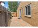 Side exterior featuring a walkway and small door between a gate and tan brick building at 2690 Magnolia St, Denver, CO 80207