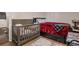 Bedroom featuring a crib, bed with red covers, wood flooring and an area rug at 3685 S Hooker St, Englewood, CO 80110