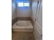 Bright bathroom featuring a tiled tub, complemented by a tiled floor at 1985 Basil St, Strasburg, CO 80136