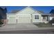 Charming home featuring an attached two-car garage, complemented by stone accents and a well-manicured lawn at 1985 Basil St, Strasburg, CO 80136