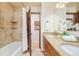 Well-lit bathroom featuring a bathtub, tiled walls, a double vanity, and granite counters at 3025 S Norman Ct, Denver, CO 80224