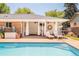 Backyard pool with connected outdoor living area, featuring covered patio and stylish furniture at 3025 S Norman Ct, Denver, CO 80224
