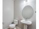 Powder room featuring a pedestal sink, oval mirror, and a modern toilet at 21234 E 63Rd Dr, Aurora, CO 80019