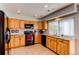 Well-lit kitchen featuring knotty wood cabinets, black appliances, and tile flooring at 2870 S Ursula St, Aurora, CO 80014