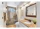 Elegant bathroom features a tiled glass enclosed shower, marble countertop, and decorative bronze framed mirror at 6681 Secrest Cir, Arvada, CO 80007