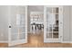 View through French doors to an elegant dining room, showcasing wood floors and a modern light fixture at 6681 Secrest Cir, Arvada, CO 80007