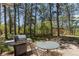 Back patio with outdoor table and grill, nestled among trees with a playground in the distance at 2045 Pine Wood Rd, Sedalia, CO 80135