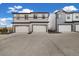 Modern townhomes display neutral-toned siding, attached garages, and large concrete driveways under a bright sky at 12570 Boggs St, Parker, CO 80134