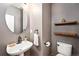 Compact powder room with a pedestal sink, decorative shelves, and a modern round mirror at 230 W Jamison Cir # 31, Littleton, CO 80120