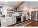 Modern kitchen with white cabinets, stainless steel appliances, open shelving, and hardwood floors at 6361 S Spotswood Cir, Littleton, CO 80120