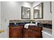 Bathroom with dark wood cabinet, black countertop, double mirrors, and white walls at 12592 E Bates Cir, Aurora, CO 80014