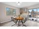 Bright dining area featuring a round wood table, stylish metal chairs, and natural light from a large window at 12592 E Bates Cir, Aurora, CO 80014