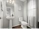 Stylish half-bathroom with pedestal sink, toilet, and decorative mirror at 5562 Gibraltar St, Denver, CO 80249