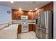 Well-lit kitchen with stainless steel refrigerator, white appliances, and wooden cabinets at 2239 Calais Dr # E, Longmont, CO 80504