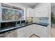 Bright kitchen features white cabinets, black countertops, and a unique backsplash beneath a large window at 22 S Indiana Pl, Golden, CO 80401