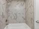 Updated bathtub and shower combination with modern showerhead and stylish marble-patterned tile at 8260 Washington St # 78, Denver, CO 80229
