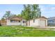 Single-story home featuring a detached garage, front porch, and a green lawn at 1057 S Osceola St, Denver, CO 80219