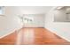 An empty living room boasts shiny hardwood floors, white walls, and ample natural light from a large window at 1057 S Osceola St, Denver, CO 80219