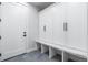 Clean mudroom featuring custom white storage cabinets, seating and modern flooring at 1157 Jersey St, Denver, CO 80220