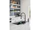 Stylish kitchen displaying open shelves on blue tiled backsplash, a modern black faucet, and sleek countertops at Reunion Freunion F Mobile St, Commerce City, CO 80022