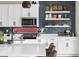 Close up of kitchen featuring updated white cabinets, stainless steel microwave, sink, and blue backsplash with open shelves at Reunion Freunion F Mobile St, Commerce City, CO 80022